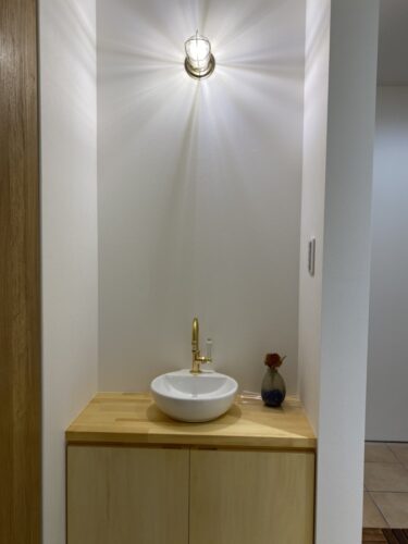 水栓は手洗いボウルに直付けのタイプ。グルーネックのゴールド色。照明にはマリンランプ水栓に合わせて同じゴールドに。